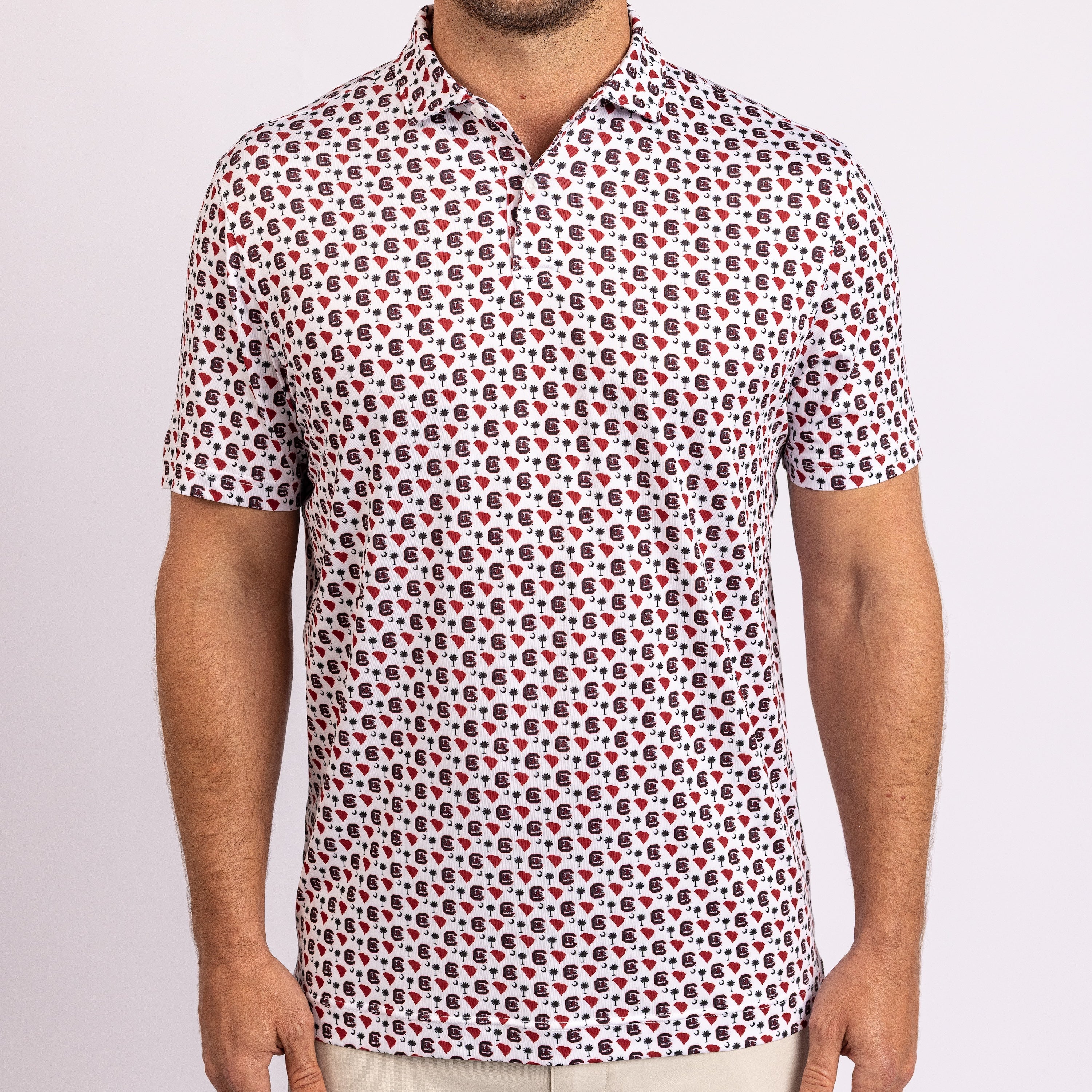 A man wearing a short-sleeve polo shirt with an all-over repeating red, black, and blue floral pattern on a white base, shown from the neck down against a plain light background.