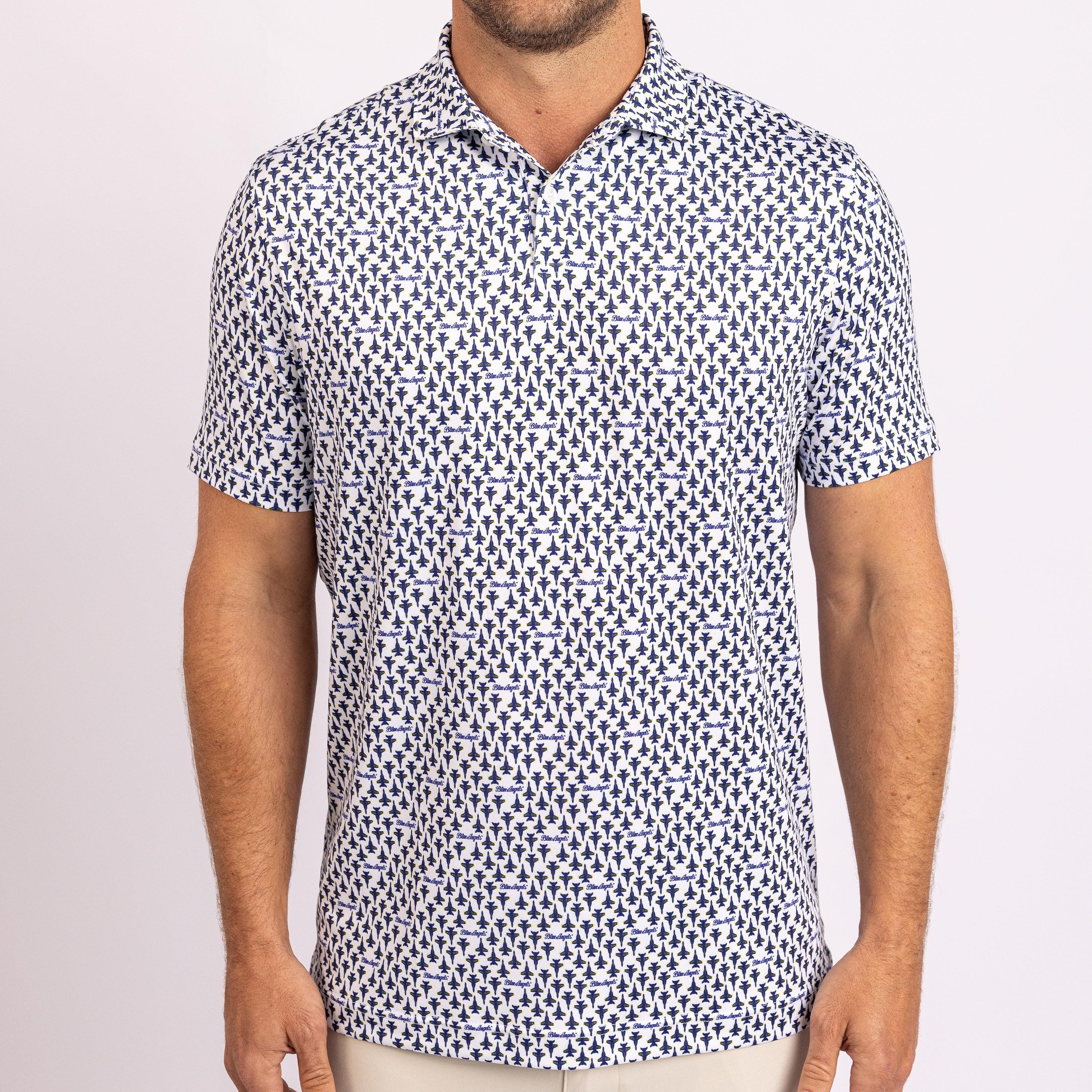 A man wearing a short-sleeve button-up polo shirt with a dense navy blue and white geometric pattern, shown from the neck down against a light studio background.