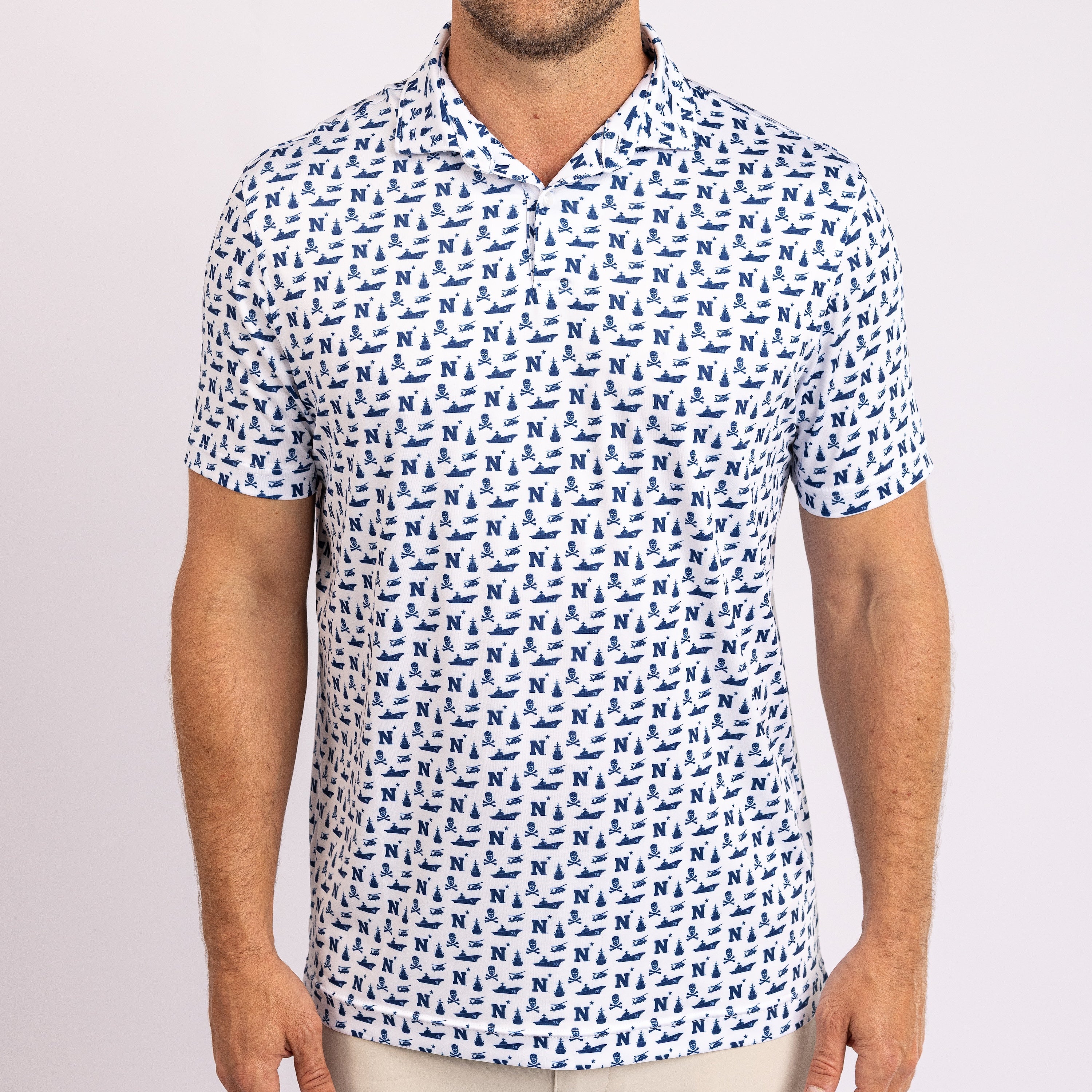 A man wearing a white short-sleeve polo shirt with a repeating blue pattern of small boats or anchors, shown from the neck down against a light gray studio background.