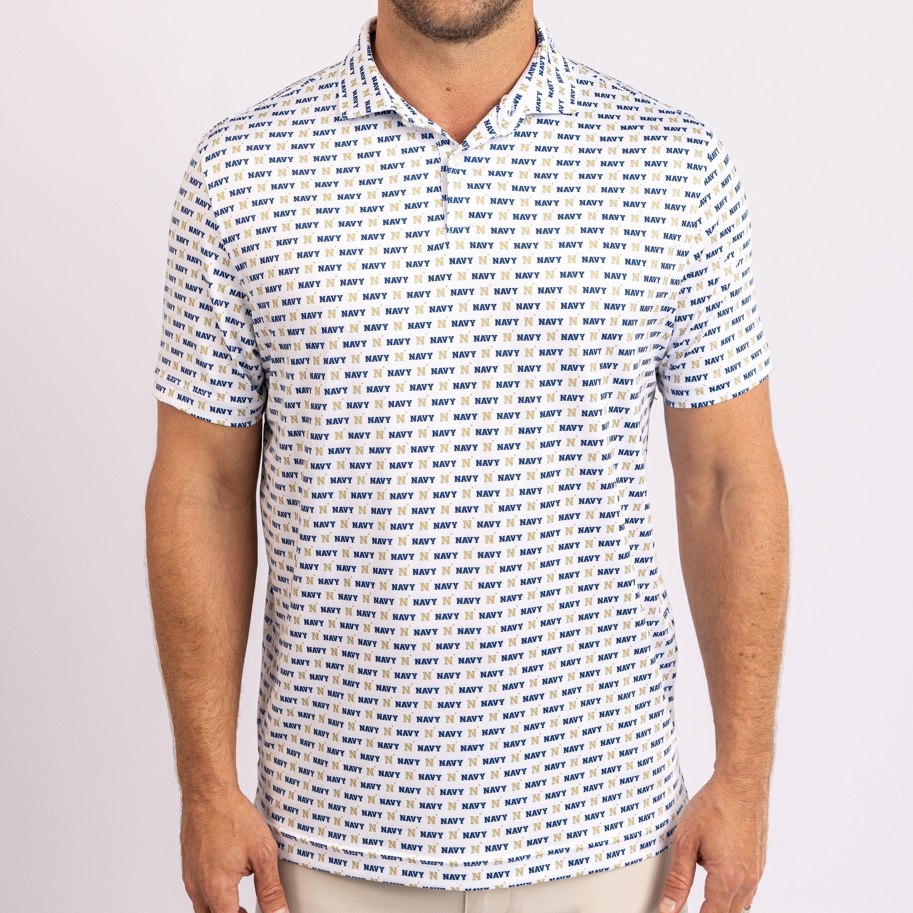 A man wearing a short-sleeve polo shirt with an all-over navy blue 'NAVY' text pattern on a white background, shown from the neck down against a light gray studio backdrop.
