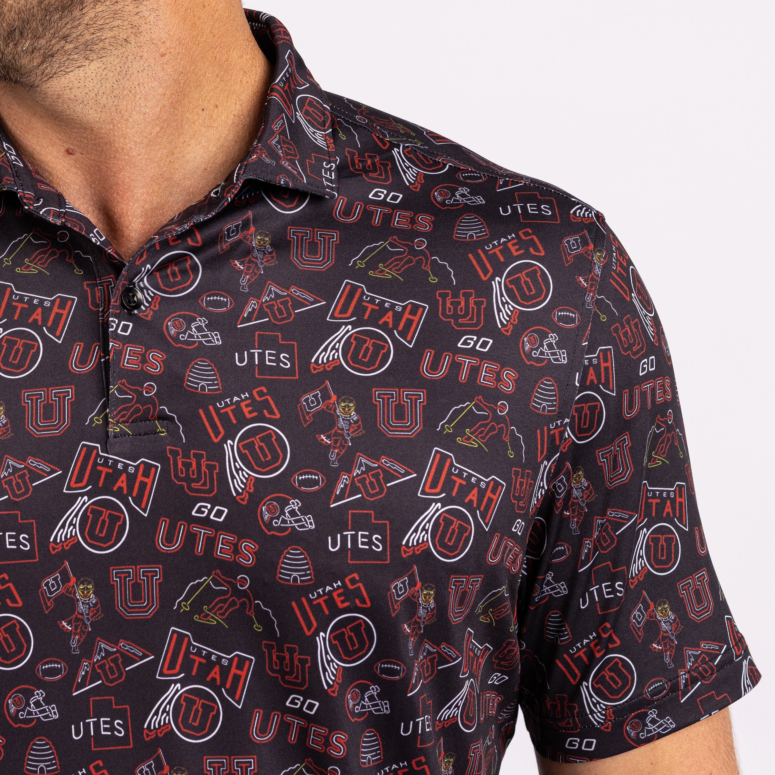 Close-up of a man wearing a short-sleeve collared polo shirt with an all-over Utah Utes sports logo print in red, white, and black.