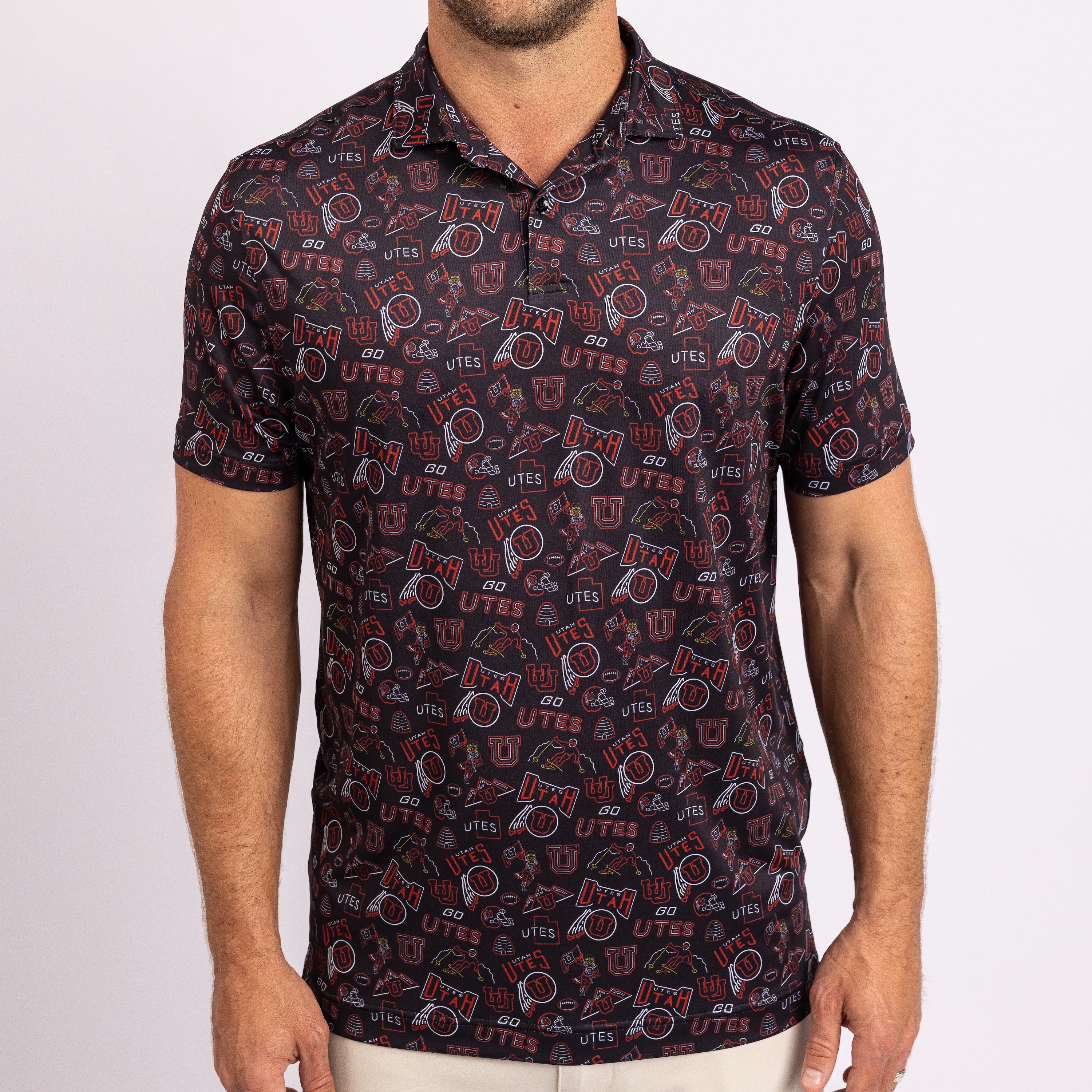 A man wearing a short-sleeve polo shirt with an all-over University of Utah Utes logo print, shown from the waist up against a light gray background.